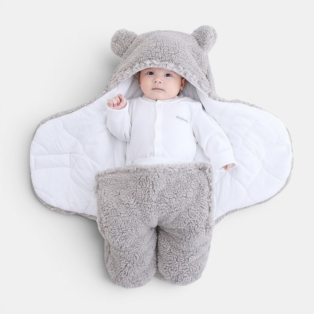 Allzom baby quilted sleeping bag and swaddle wrapper in grey teddy fleece with bear hood. Features a white quilted lining and separate leg sections.