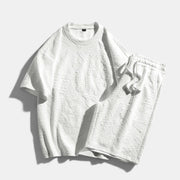 Conjunto desportivo Allzom branco de manga curta com calções, em malha texturizada com padrão de letras em relevo.