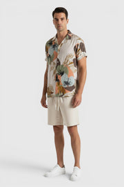 Homem veste conjunto Allzom de camisa de manga curta com padrão floral abstrato e calções bege casuais de verão