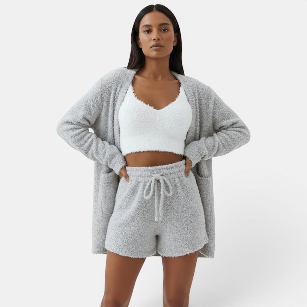 Mulher com conjunto de pijama Allzom de 3 peças em cinza, com top curto branco, tank e calções em tecido felpudo.