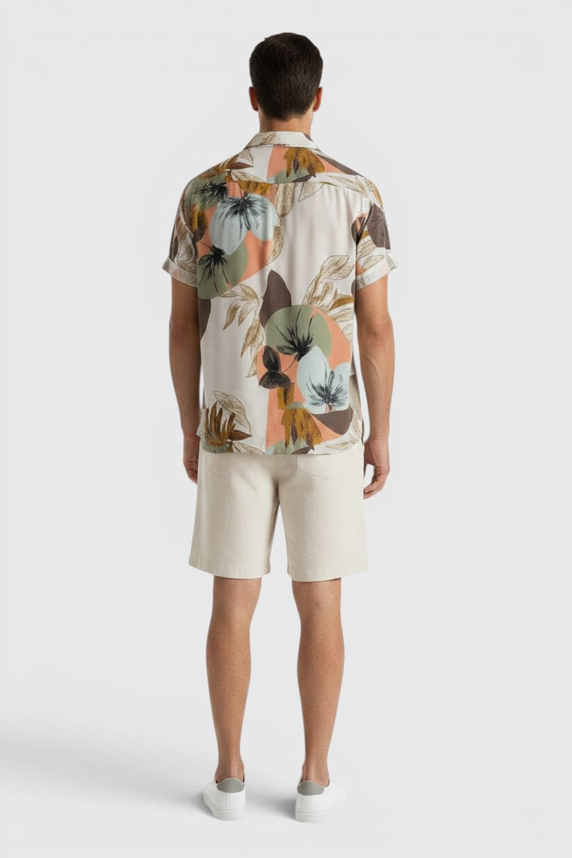 Homem de costas vestindo conjunto Allzom de camisa de manga curta com estampa floral e calções bege em fundo branco