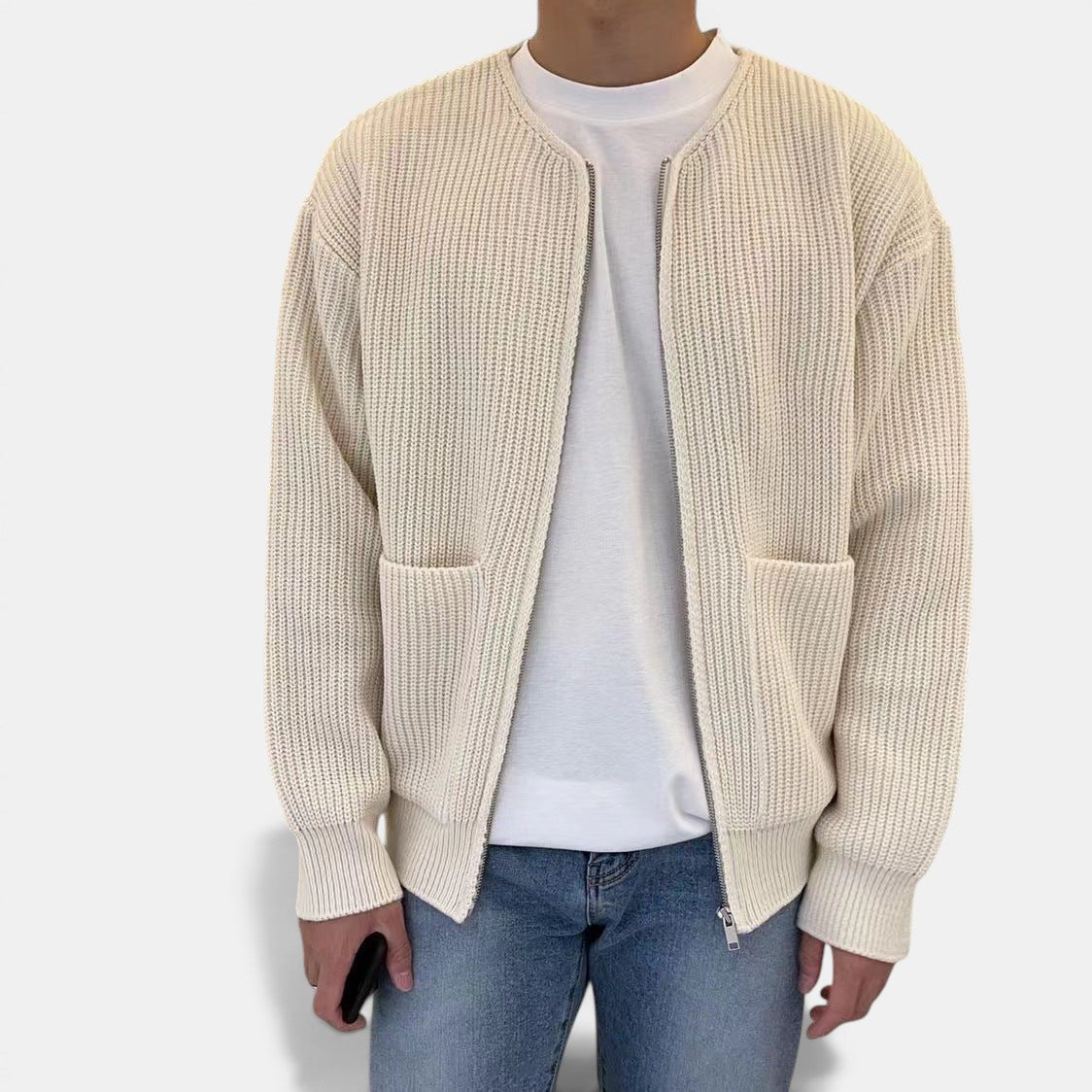 Allzom cream knitted zip-up cardigan with pockets and funnel neck, worn over a white t-shirt and blue jeans.