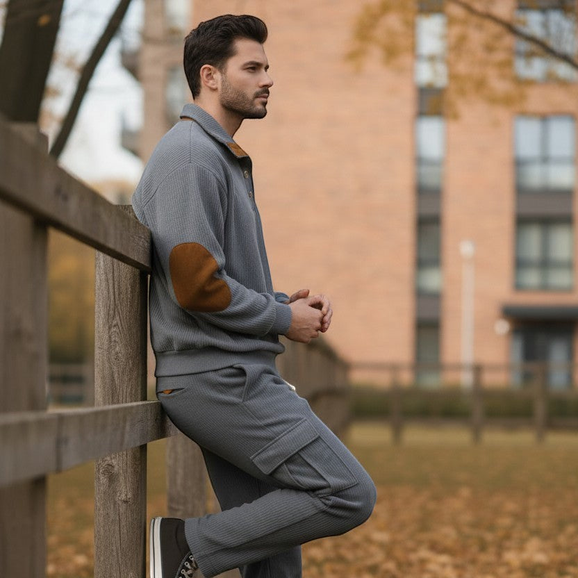 Allzom grey corduroy sweatshirt set with stand collar and elbow patches, and matching cargo pants. Model leaning on fence.
