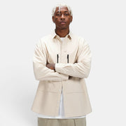 Allzom Men's beige long-sleeve shirt jacket with zipper pockets and button closure. Model is wearing it over a white t-shirt.