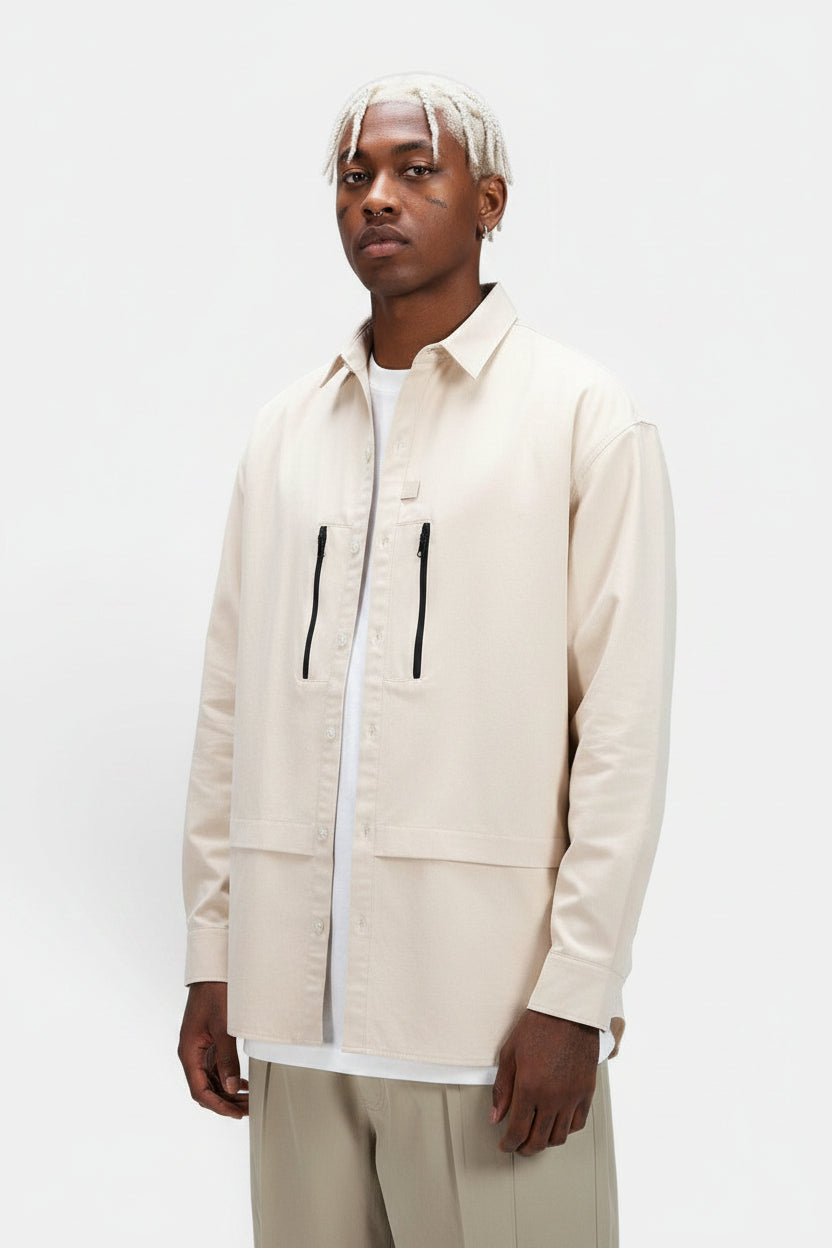 Allzom Men's beige long-sleeve shirt jacket with zipper pockets and button closure. Model is wearing it over a white t-shirt.