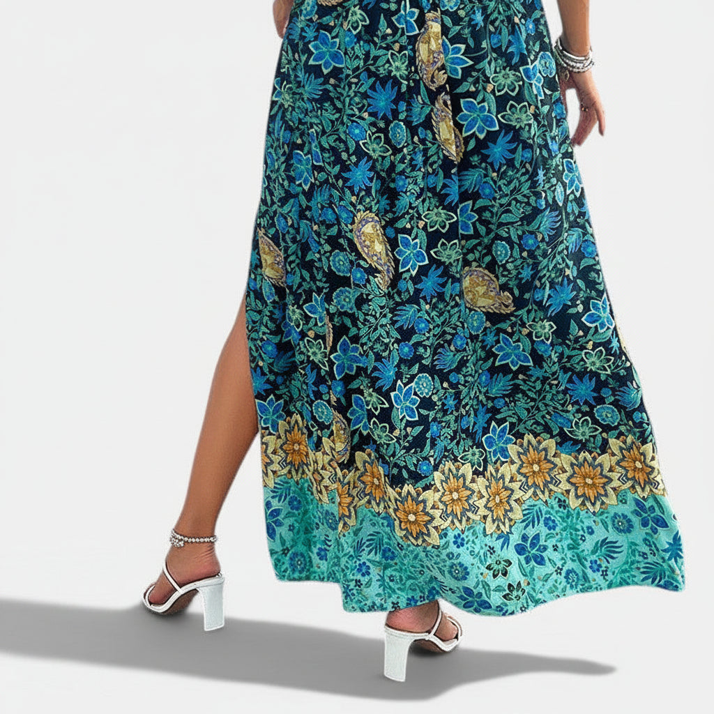 Allzom Vestido preto com alças finas, estampado de flores e plantas em tons de azul e amarelo, cintura alta, saia longa com fenda lateral.